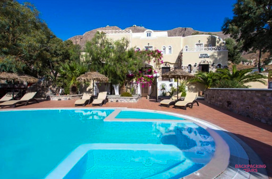 Enjoying the sun by the sparkling blue pool at a traditional Greek island hotel in Santorini.