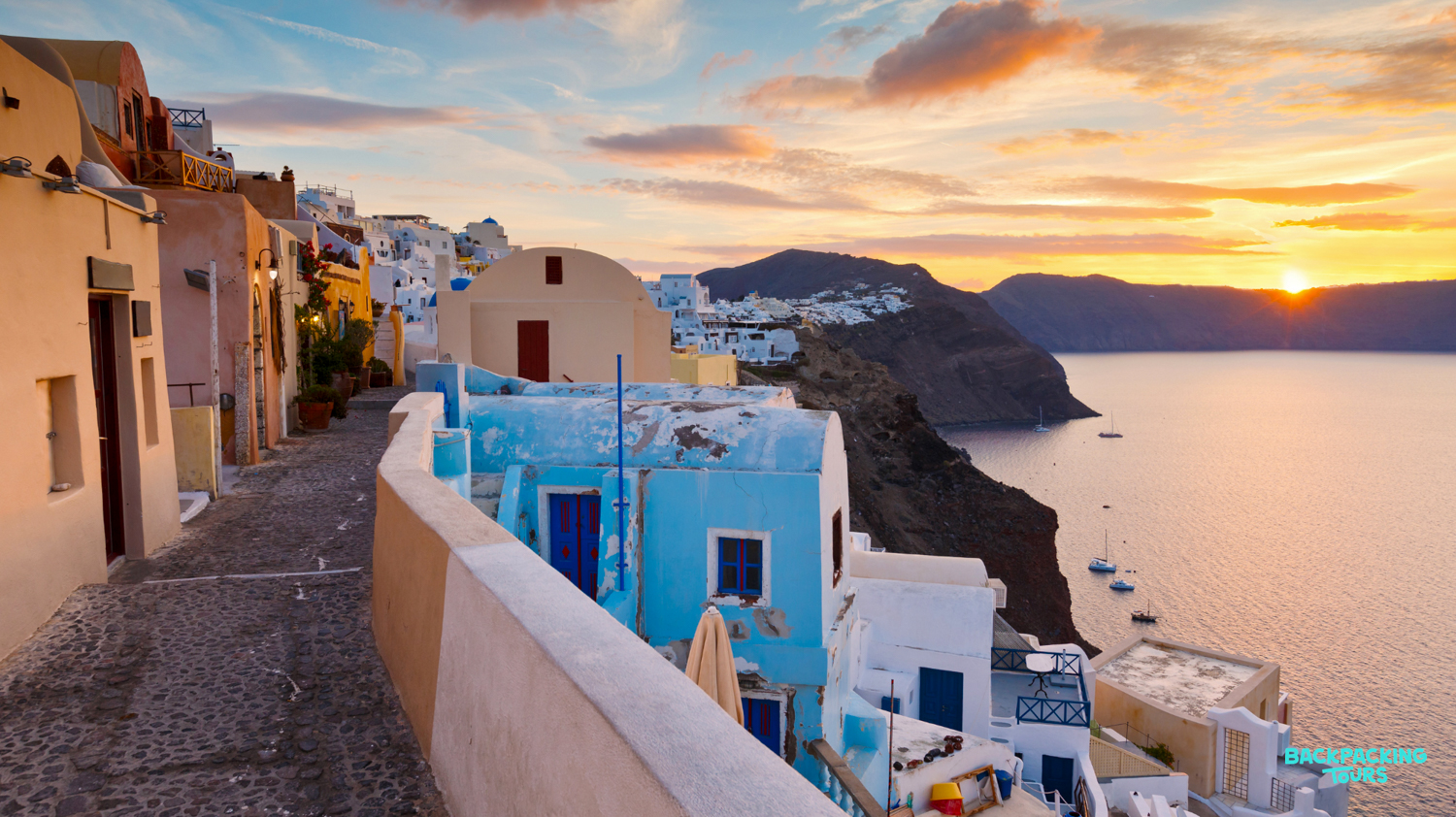 Golden hour casts a warm glow on Santorini's iconic white and blue buildings, overlooking the Aegean Sea.