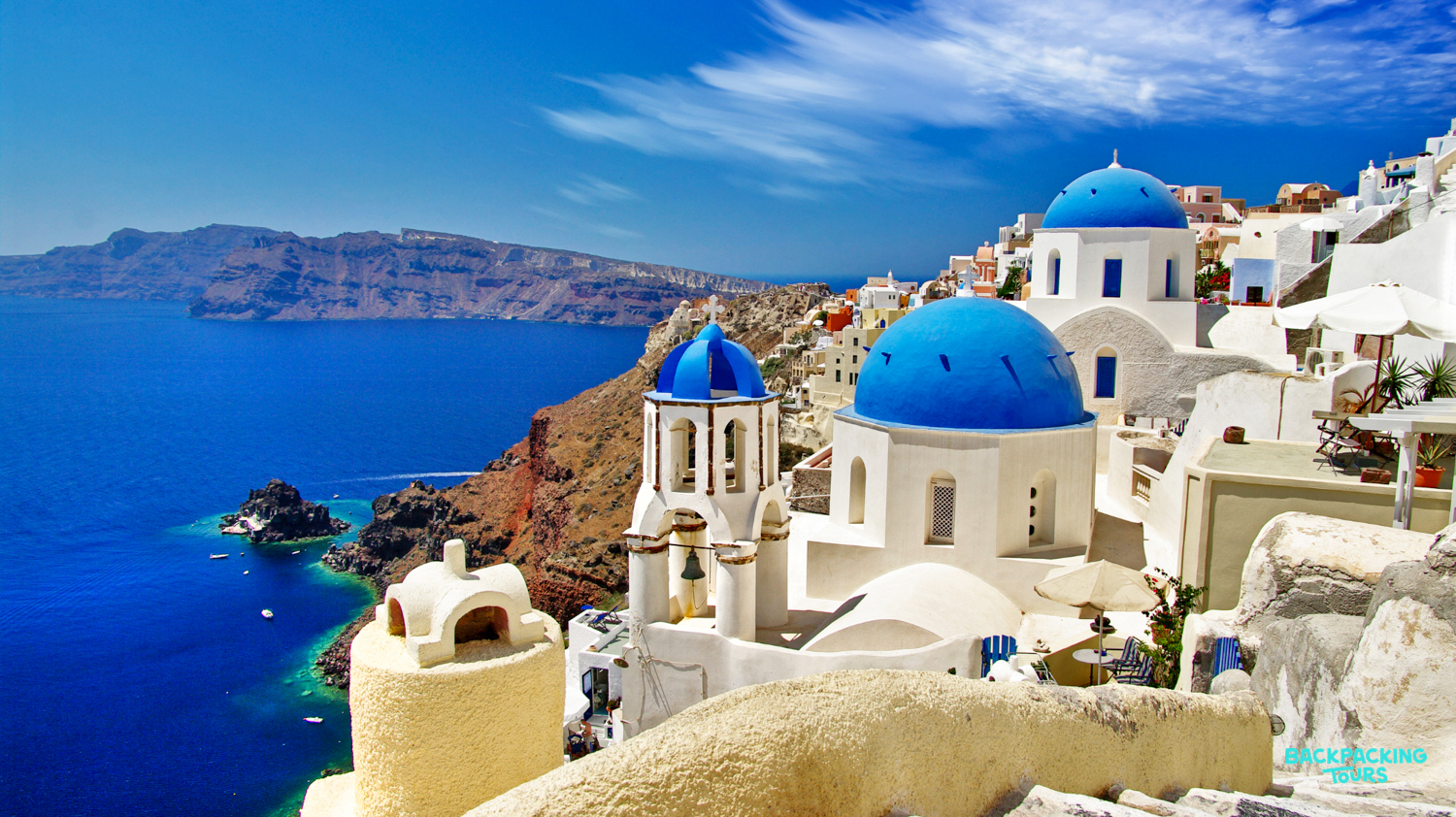 Whitewashed buildings and blue-domed churches on Santorini's cliffs overlooking the deep blue Aegean Sea.
