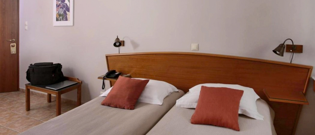 A simple hotel room in Athens with two single beds, ready for arriving backpackers.