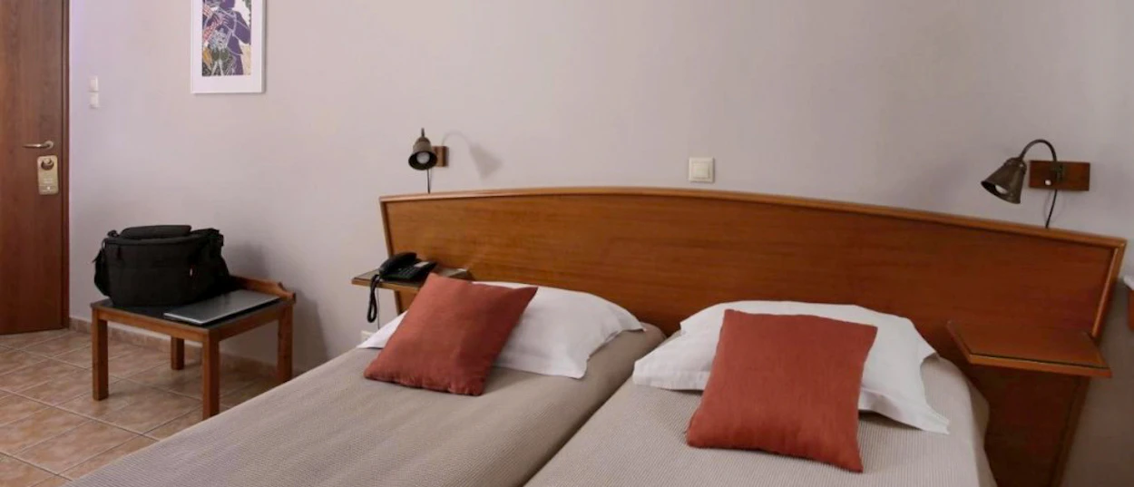 A simple hotel room in Athens with two single beds, ready for arriving backpackers.