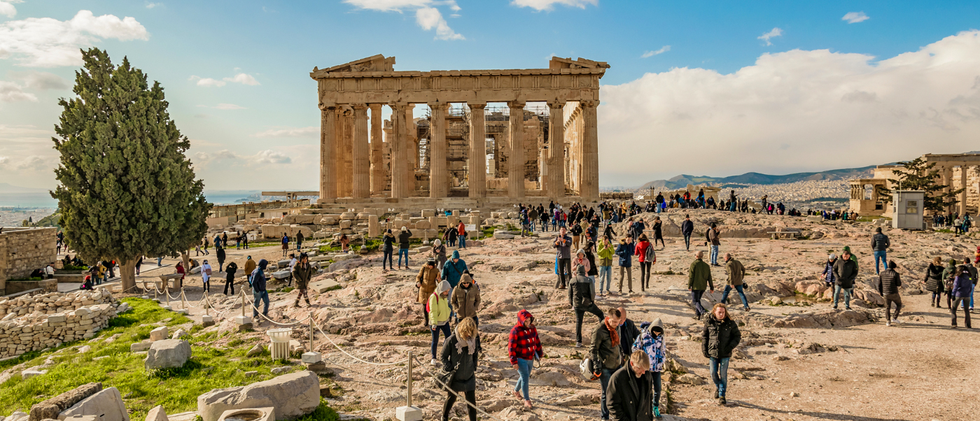 Tourists explore the ancient ruins of the Parthenon on the sunny Acropolis in Athens.