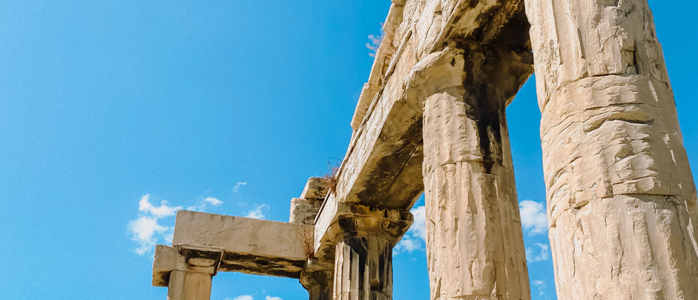 Ancient stone columns of the Parthenon stand tall against a bright blue sky in Athens.