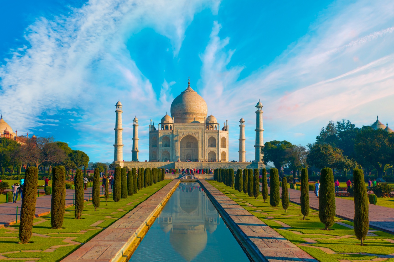 The majestic Taj Mahal in India, reflected beautifully in a long pool under a blue sky.