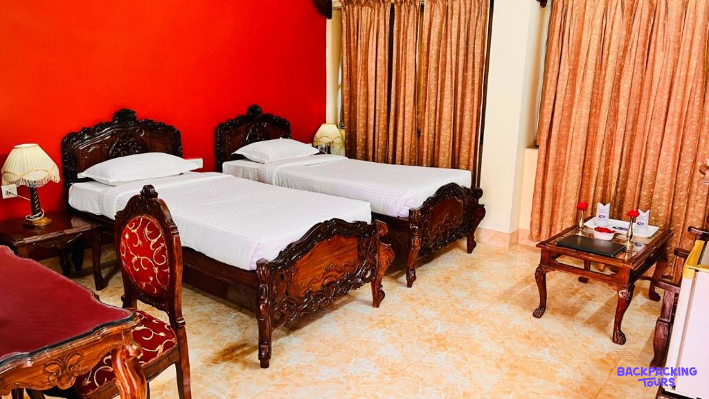 A traditional twin room in Pushkar featuring ornate wooden beds, red walls, and patterned curtains.