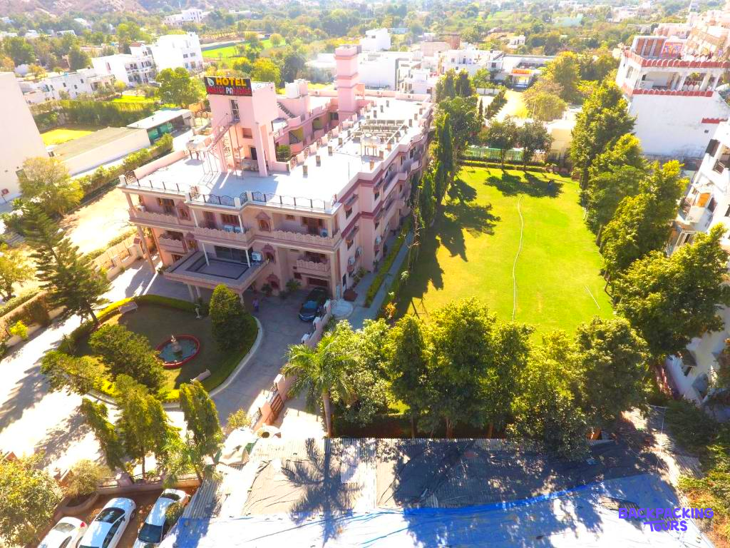 The Master Paradise hotel in Pushkar, India, featuring a large building and a vibrant green lawn.