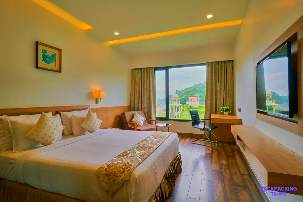 Relax in this comfortable hotel room with a large bed and a scenic view of Udaipur.