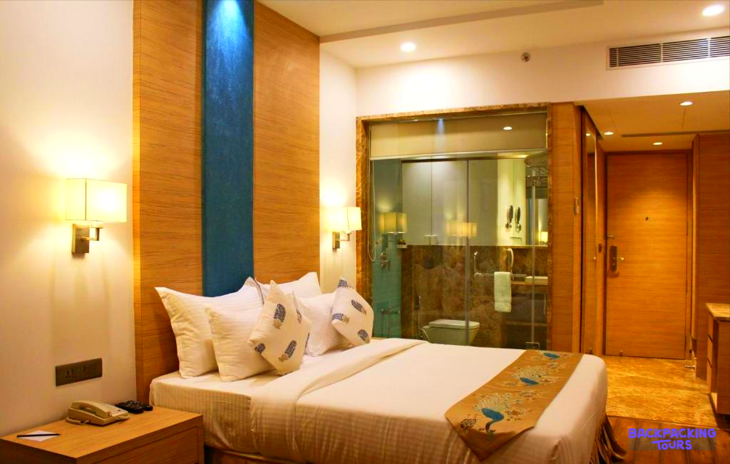 Relax in a modern hotel room in Udaipur, featuring a comfortable bed and warm lighting.