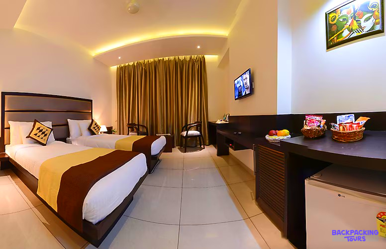 A comfortable hotel room in Agra, India, featuring two single beds and a desk.
