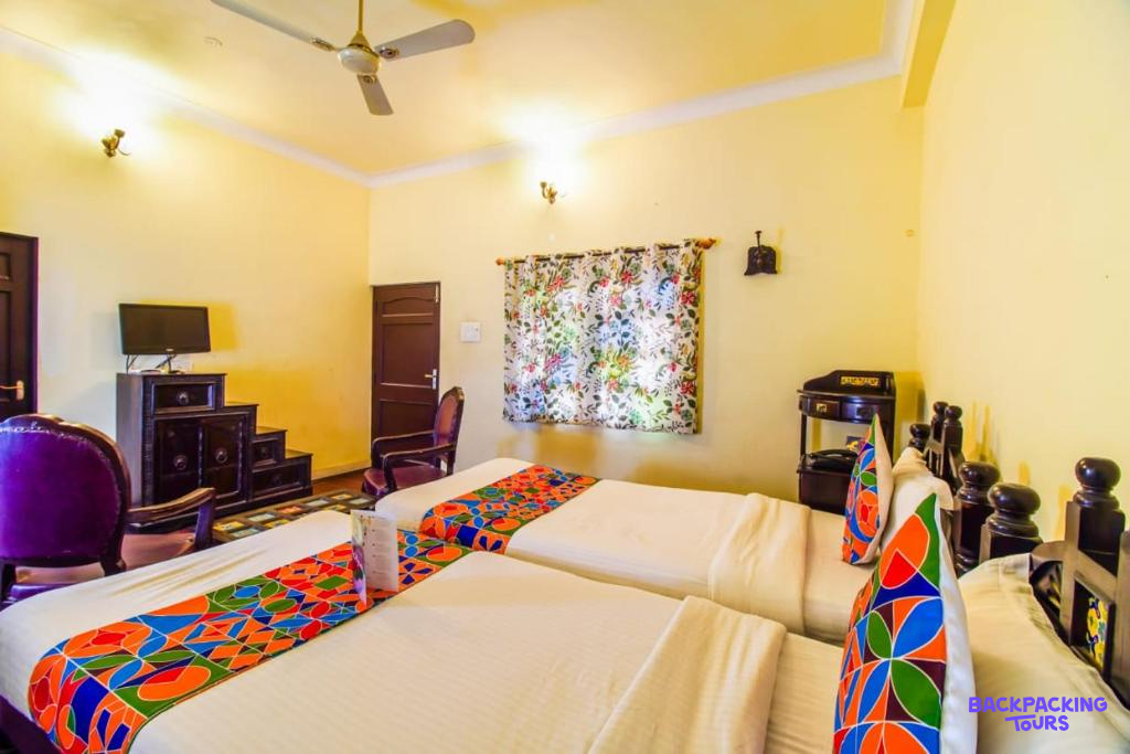 A bright twin room with colorful bedding and a ceiling fan, offering comfortable accommodation in Jaipur.