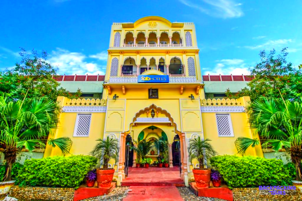 The bright yellow facade of a traditional Indian hotel, surrounded by green foliage in Jaipur.