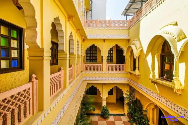 A charming yellow guesthouse courtyard in Jaipur, showcasing traditional Indian architecture and vibrant colors.