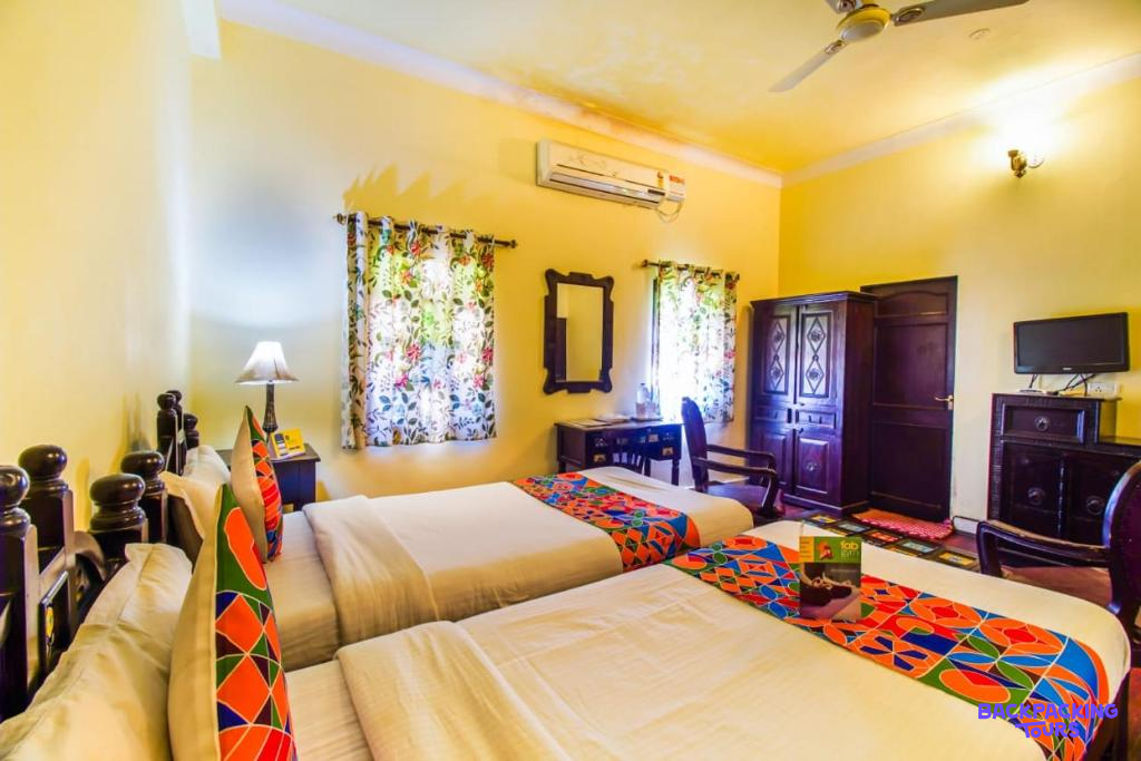 A bright and colorful twin room with patterned bedding and yellow walls in Jaipur.