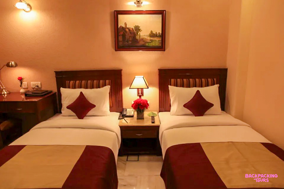 A comfortable twin room in a New Delhi hotel, featuring two single beds and warm lighting.