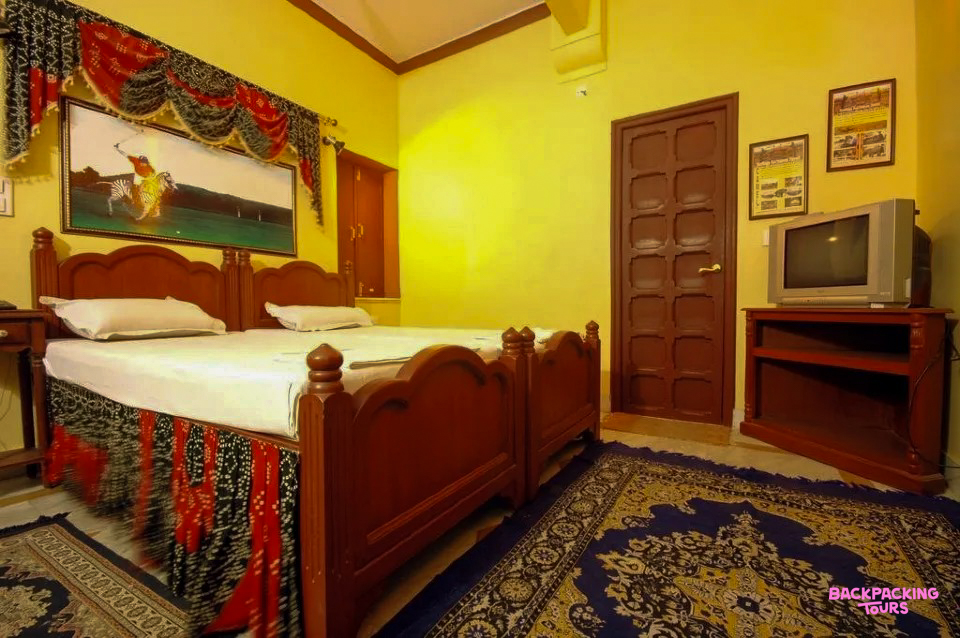A welcoming room in a Jodhpur haveli, with two beds, yellow walls, and traditional decor.