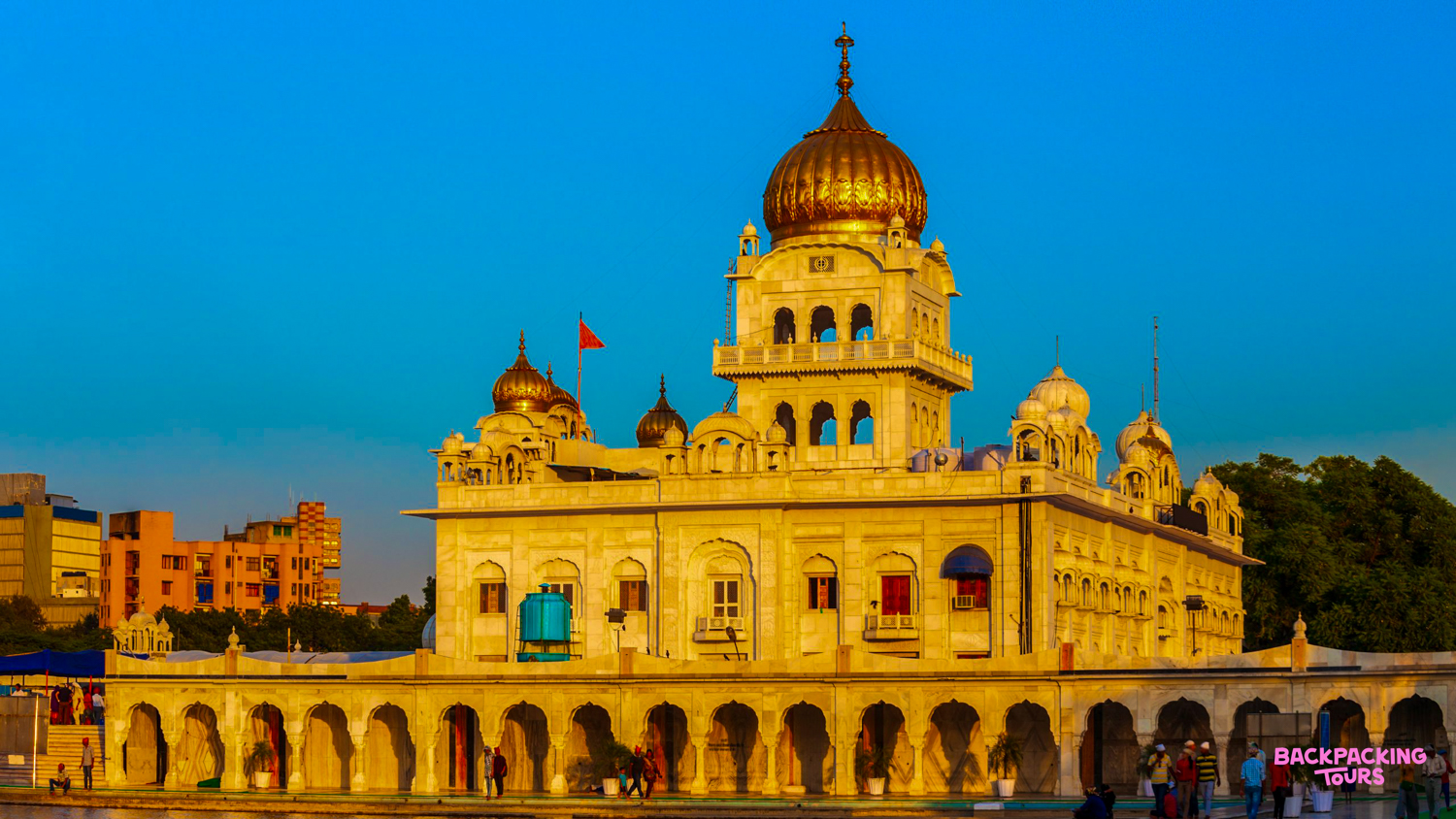 Ornate golden-domed Sikh temple in New Delhi, glowing beautifully as it reflects in the tranquil water.