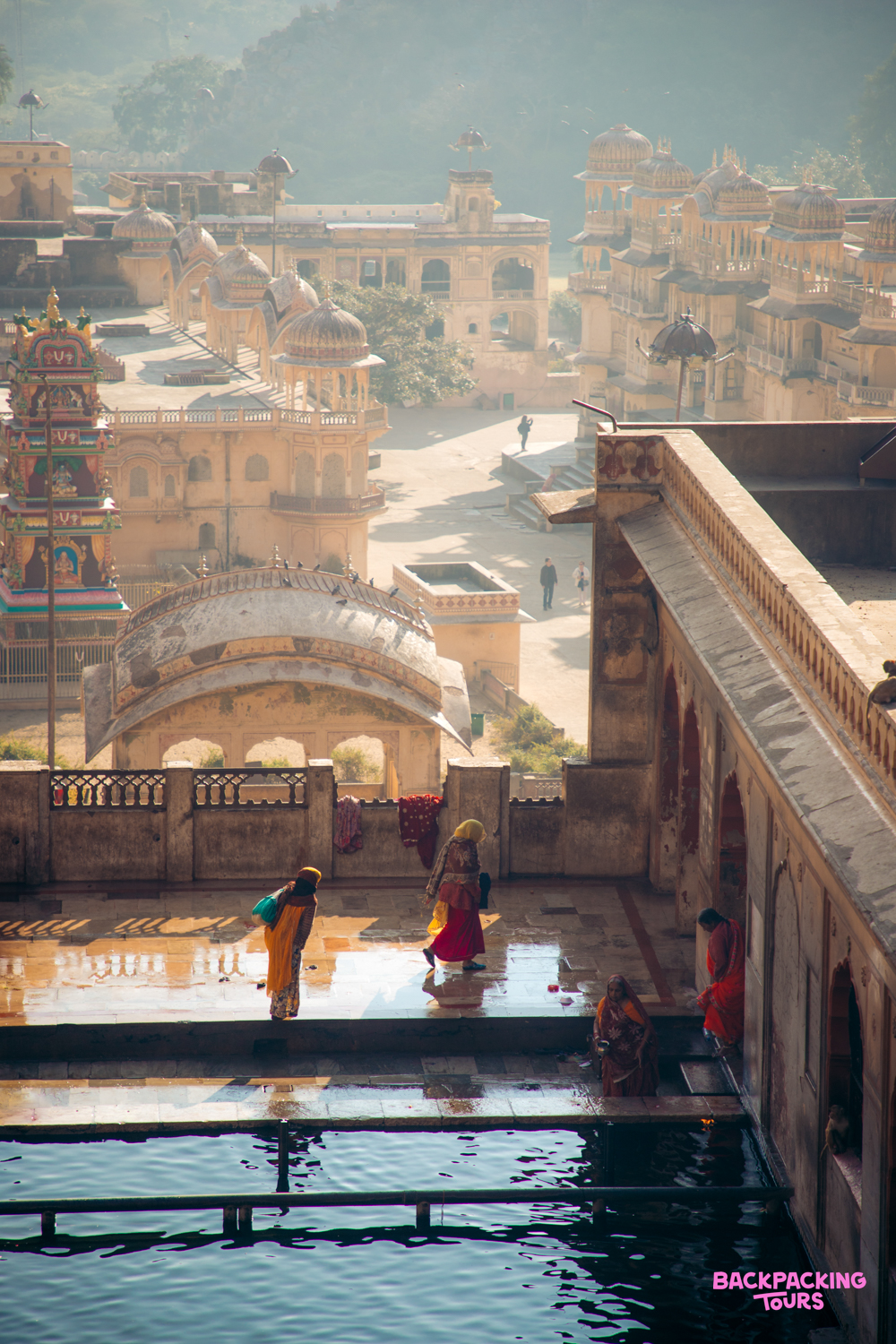 Women in colorful saris walk around the sacred stepwell of a historic temple in Jaipur.