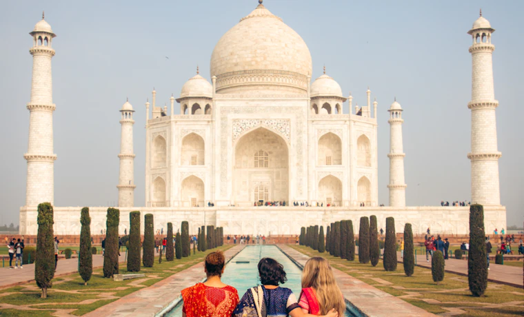 Three women in colorful saris admire the majestic Taj Mahal in Agra, India.