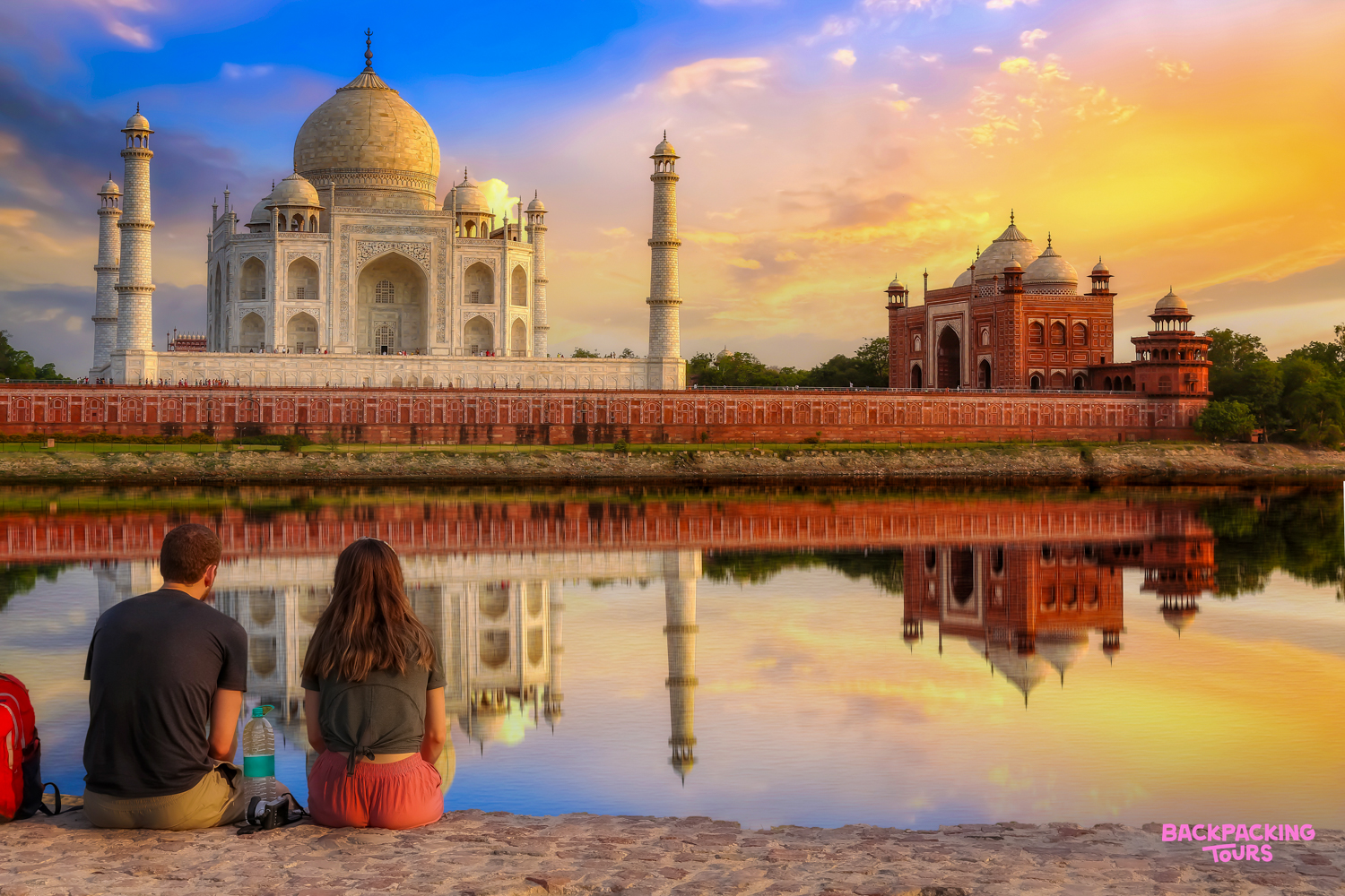 Two people admire the majestic Taj Mahal and its reflection at sunrise in Agra, India.