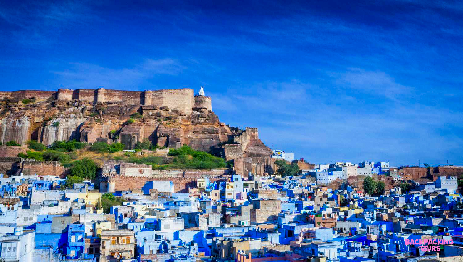 The iconic blue city of Jodhpur with Mehrangarh Fort towering above under a clear sky.