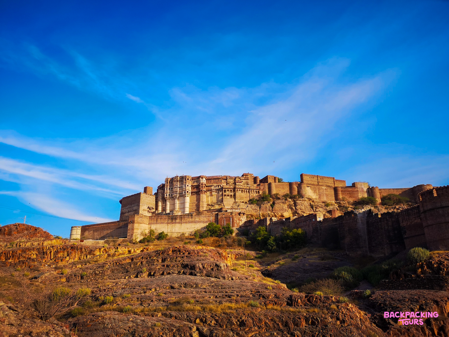 The majestic Mehrangarh Fort stands atop a rocky hill under a vibrant blue sky in Jodhpur.