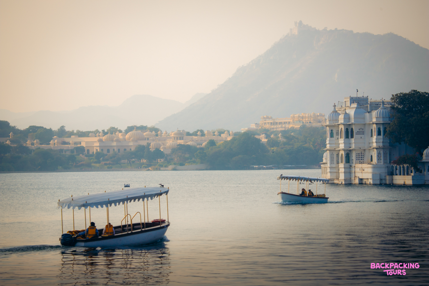 Enjoying a serene boat cruise on Lake Pichola in Udaipur, passing historic white palaces.
