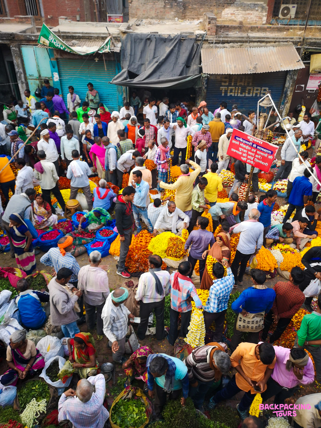 A lively flower and vegetable market in Udaipur, India, with many locals engaged in daily commerce.