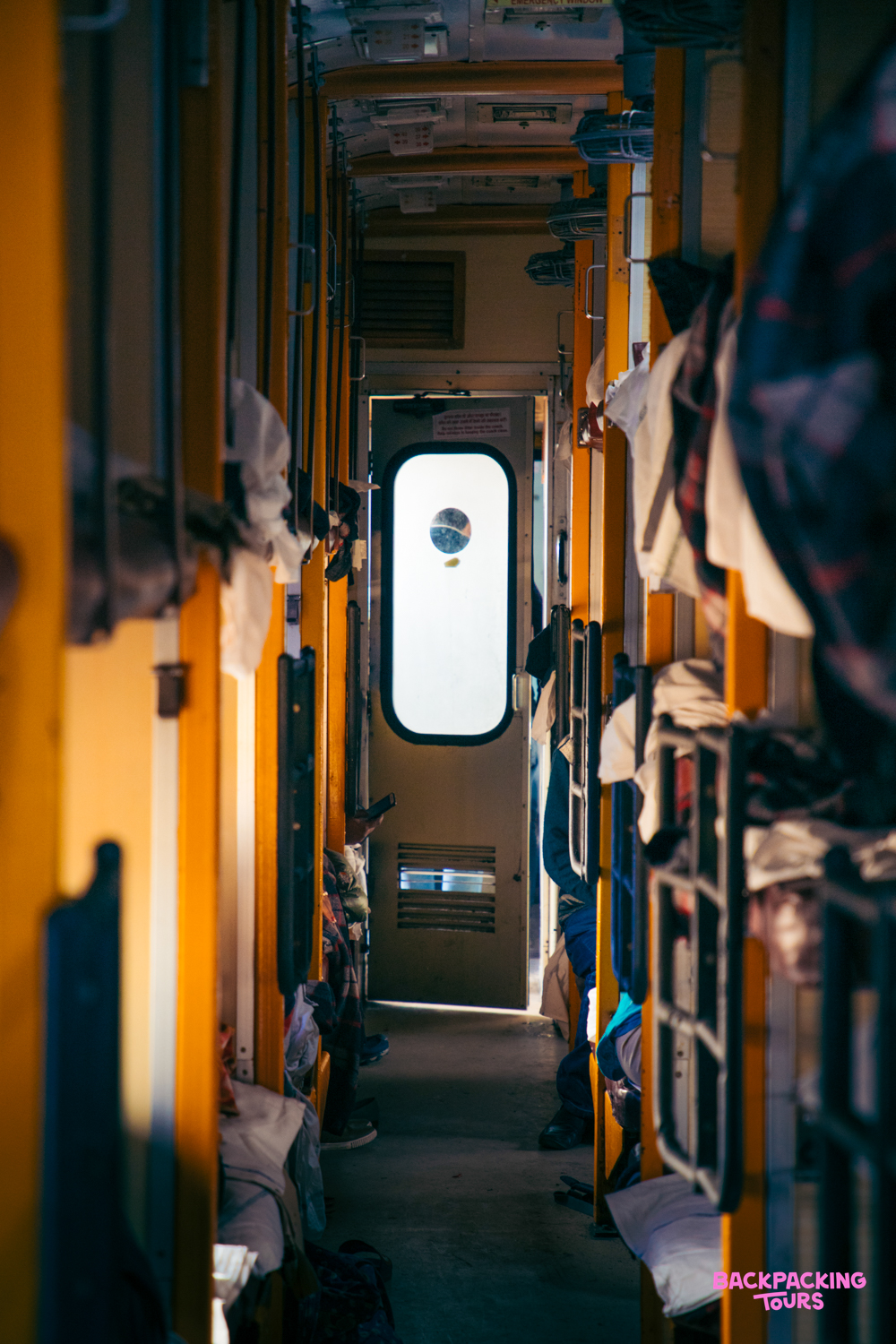 An authentic view inside an Indian sleeper train, with bunks and luggage along the aisle.