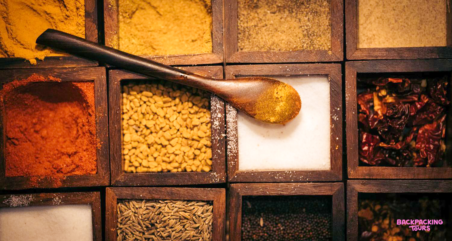 A vibrant array of Indian spices in wooden boxes, ready for a cooking class in Udaipur.