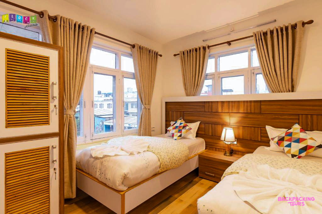 A bright and comfortable twin bedroom with two single beds and large windows in Kathmandu.