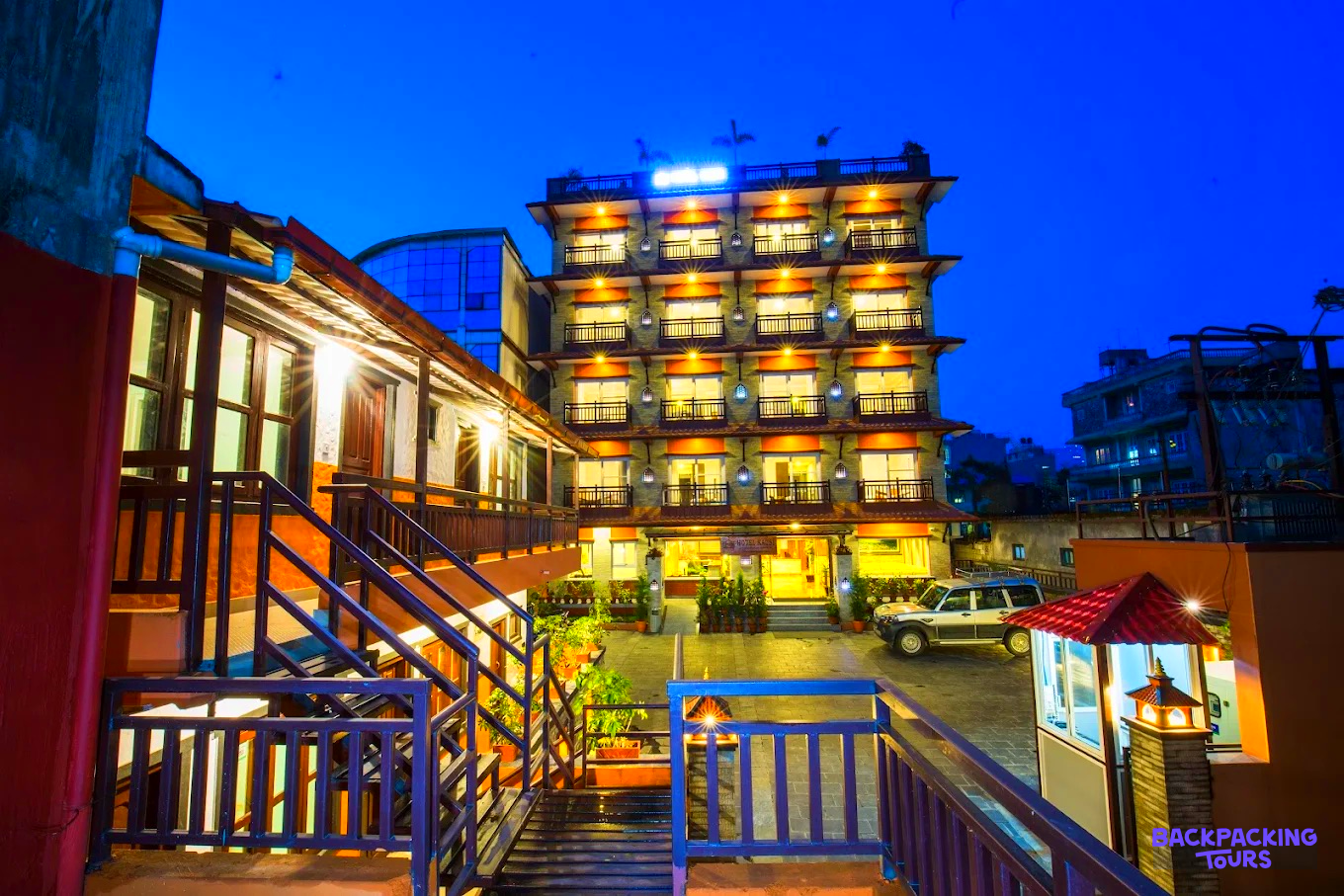 An inviting hotel exterior with warm lights and wooden stairs at dusk in Pokhara.