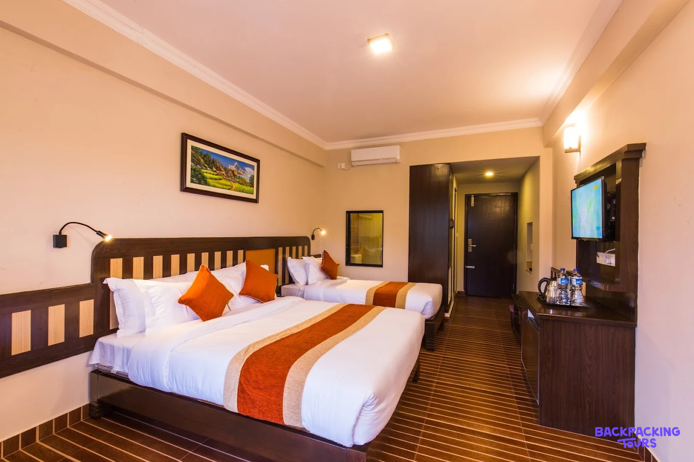 Clean and inviting hotel room in Pokhara featuring a double and single bed with orange accents.