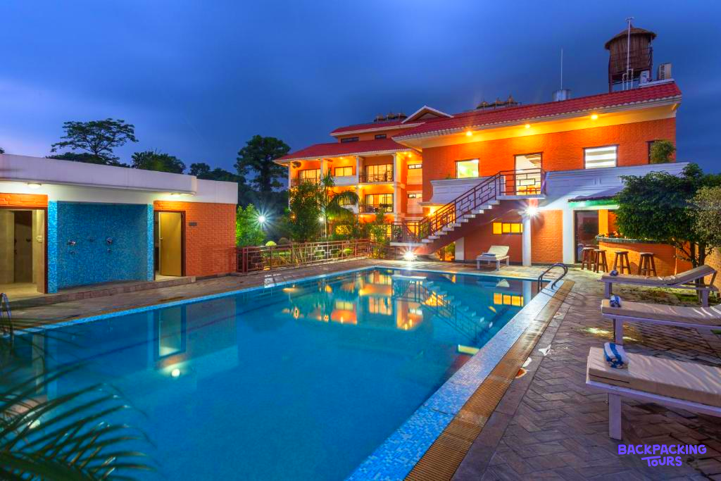 Relaxing evening at a vibrant lodge with a glowing pool, surrounded by nature in Chitwan National Park.