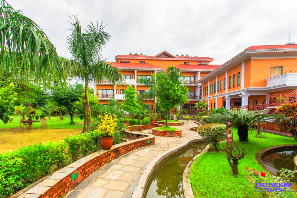 Lush green gardens and a winding path lead to a beautiful lodge in Chitwan National Park.