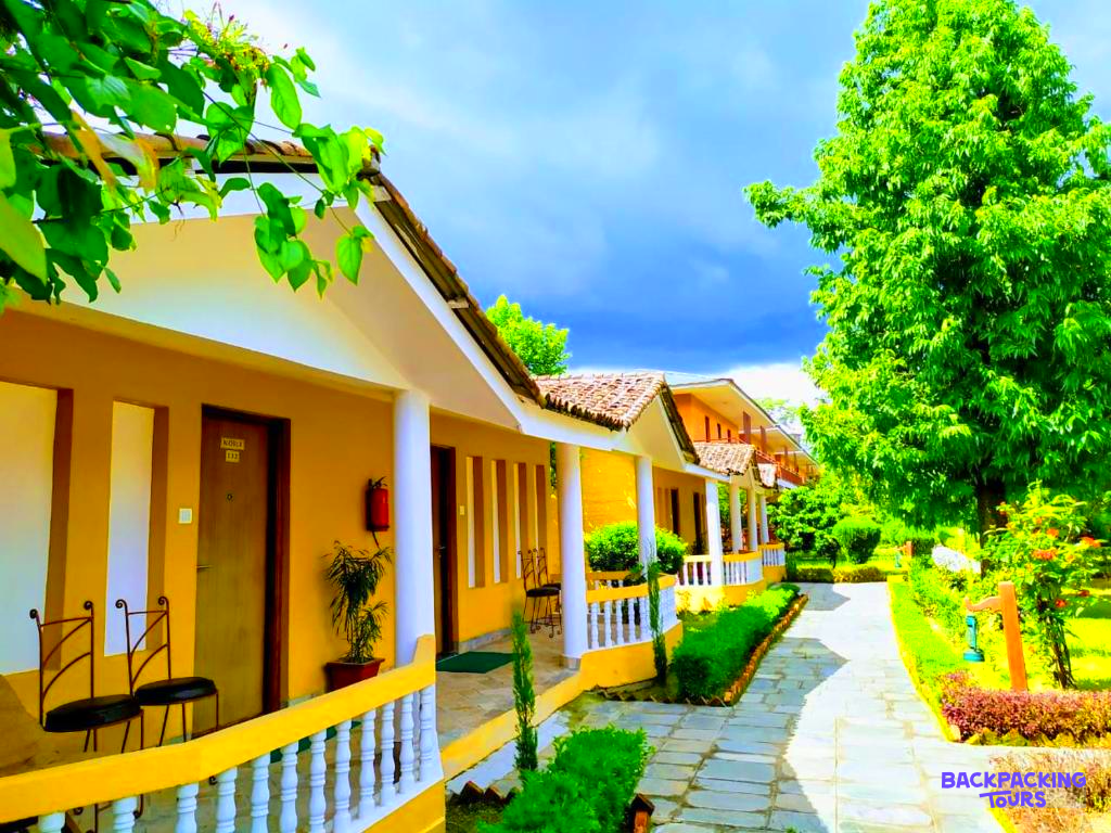 Charming yellow lodges with white railings and lush green surroundings at Chitwan National Park.