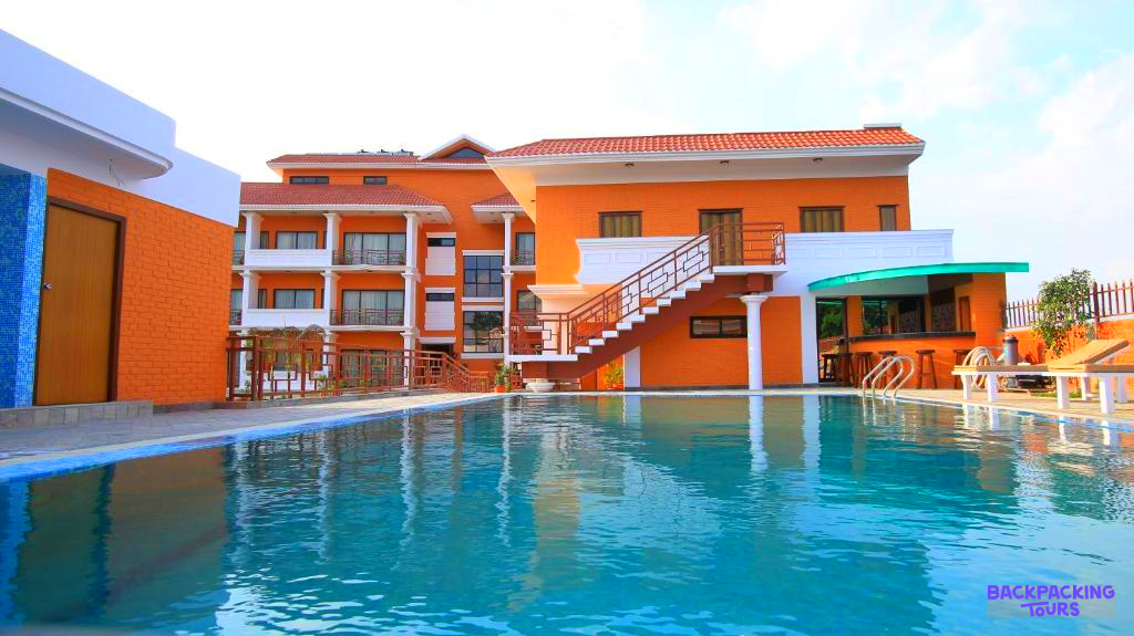 A vibrant orange lodge with a refreshing swimming pool, offering comfortable accommodation in Chitwan National Park.