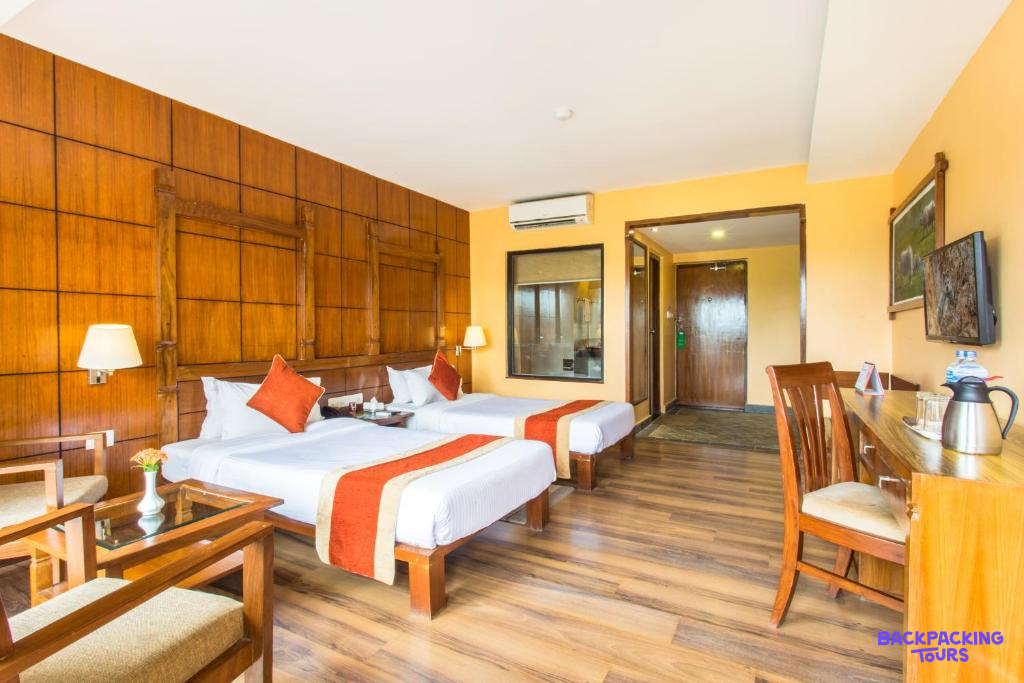 A comfortable twin room with wooden floors and warm yellow walls at a lodge in Chitwan National Park.