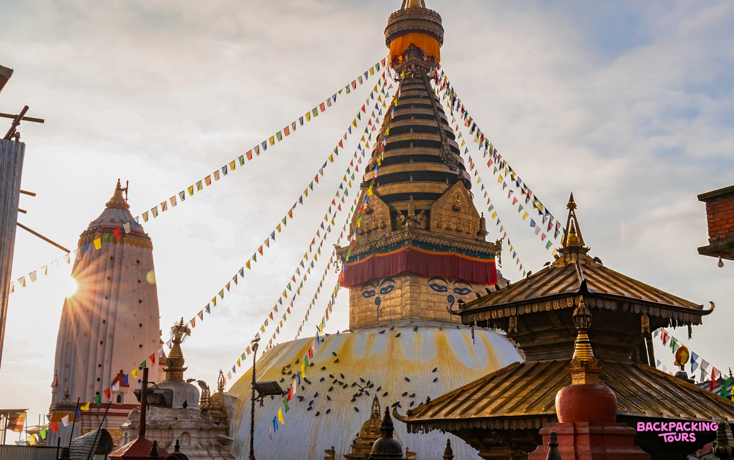 Serene Swayambhunath Stupa in Kathmandu at sunset, with many birds perched on its white dome.