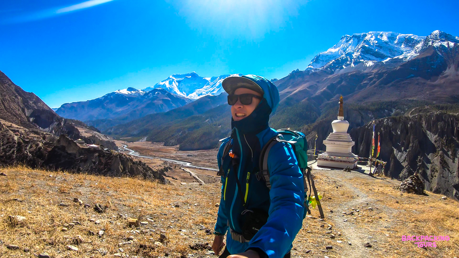 Backpacker takes a selfie at Australian Camp, overlooking a valley and the majestic Annapurna Mountains.