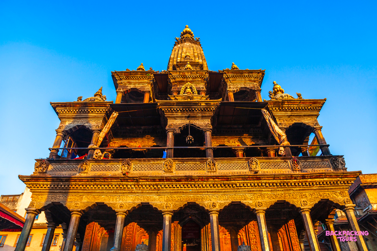 An ornate, multi-tiered wooden temple with intricate carvings at Patan Durbar Square, Kathmandu.