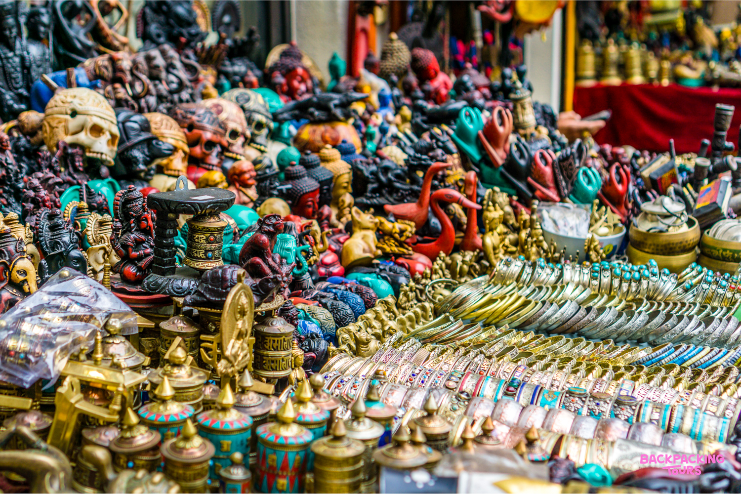 A vibrant market stall in Thamel Bazaar, Kathmandu, overflowing with colorful crafts and golden jewelry.
