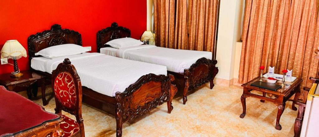 A hotel room in Pushkar with two single beds, carved wooden frames, and a bright red wall.