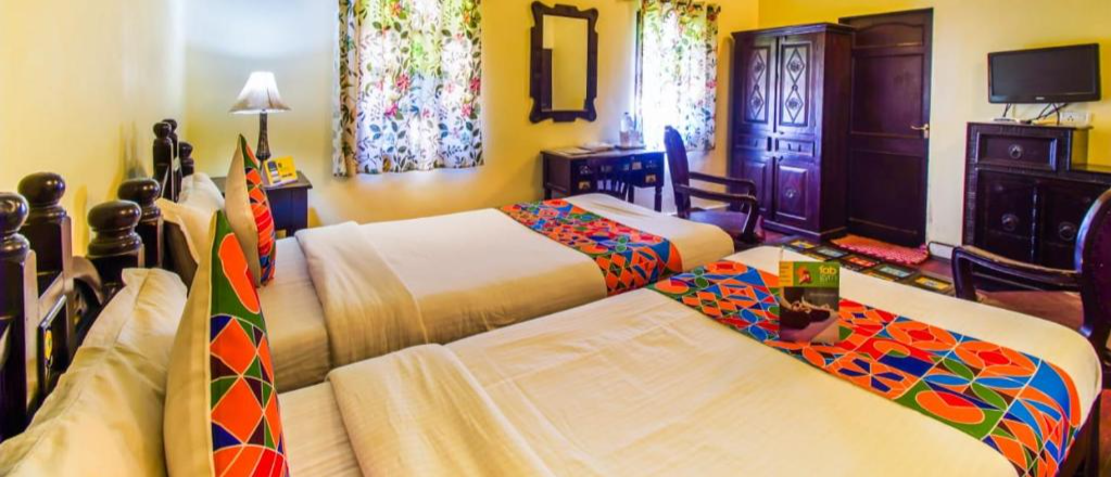 A vibrant hotel room in Jaipur with two beds, colorful textiles, and traditional wooden furniture.