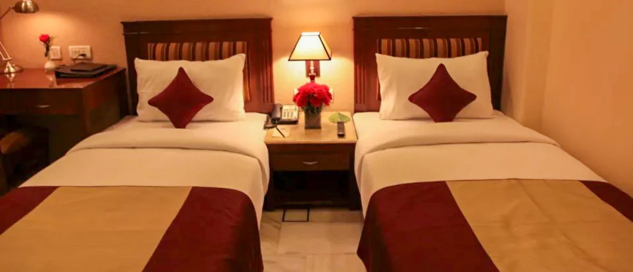 A comfortable twin room with two single beds, bedside table, and warm lighting in New Delhi.