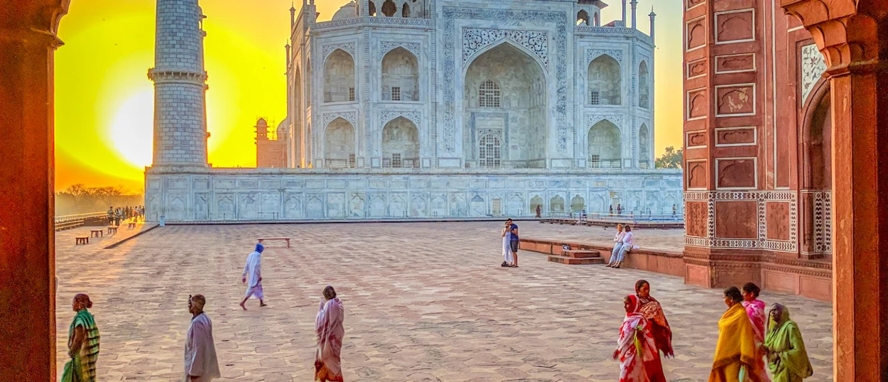 Visitors explore the majestic Taj Mahal in Agra, its white marble glowing under a golden sky.