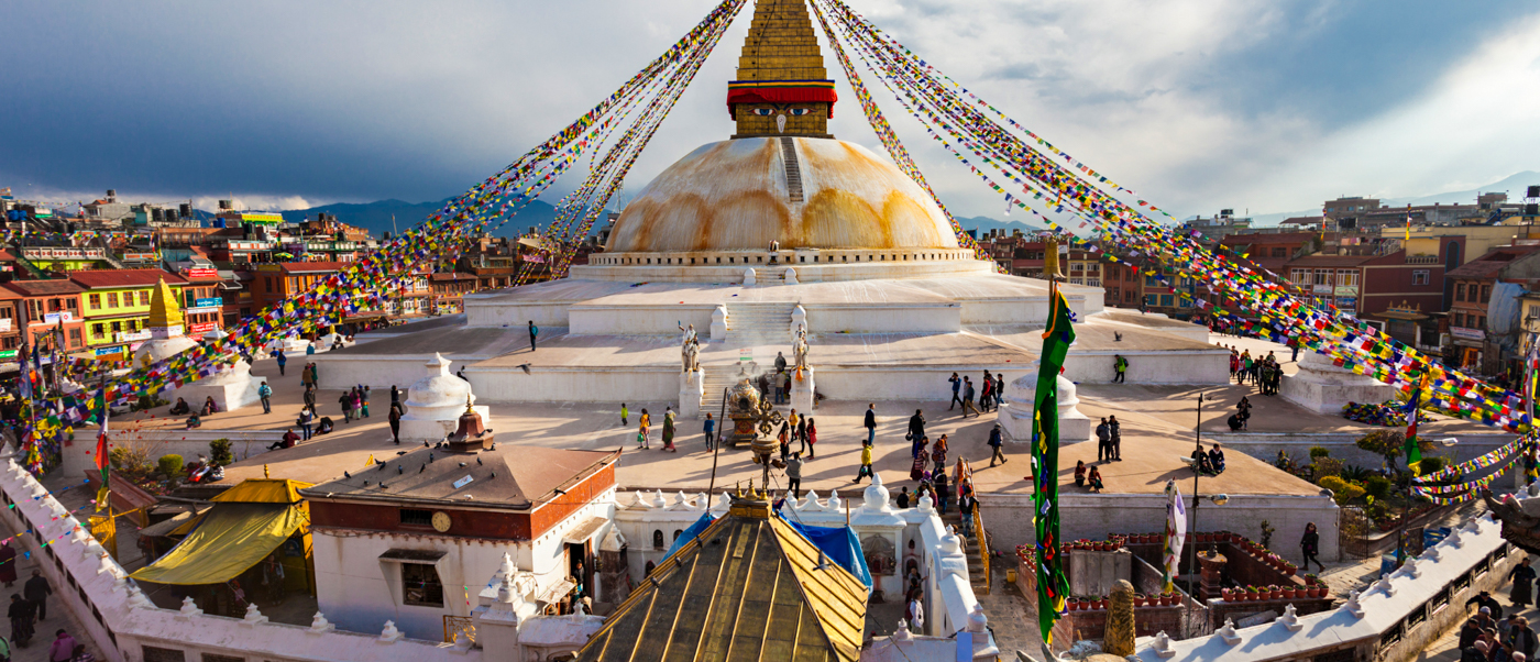 Visitors explore the serene Swoyambhunath Stupa in Kathmandu, surrounded by colorful buildings and prayer flags.