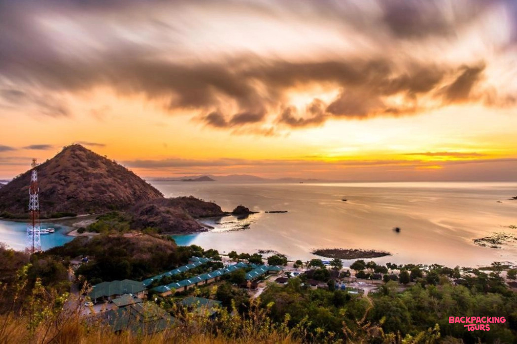 Breathtaking sunset over Labuan Bajo bay, illuminating islands and a tranquil coastal resort.