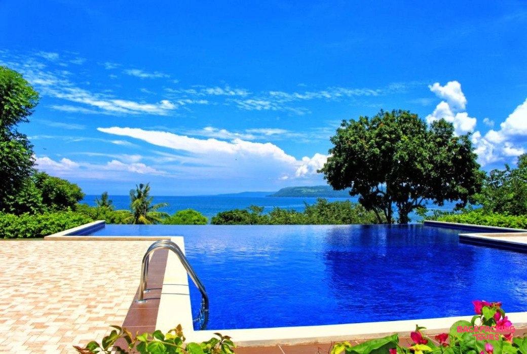 A vibrant blue infinity pool offers stunning views of the ocean and distant land in Sumbawa.