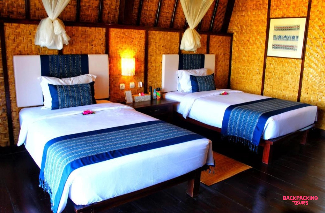 Comfortable twin beds in a rustic room with bamboo walls and draped mosquito nets in Sumbawa.