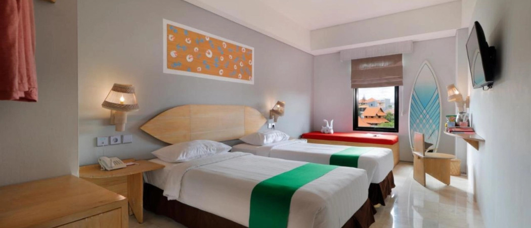 A bright, surf-themed twin hotel room in Canggu, Bali, with two beds and a window view.